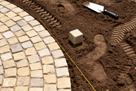 A close-up shot shows the process of laying paving stones, with a string line and trowel visibleの素材