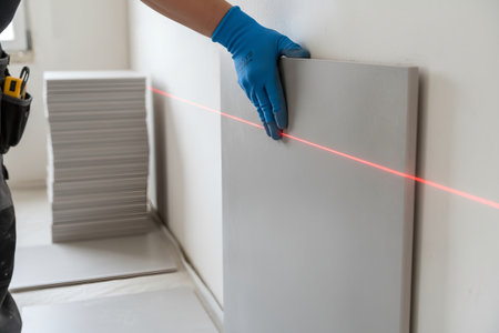 A construction worker uses a laser level to ensure a wall panel is perfectly aligned during a home renovation projectの写真素材
