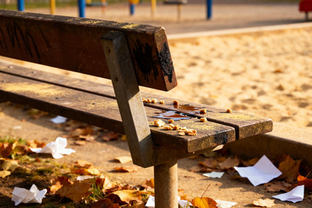 An old wooden bench is covered in crumbs, liquid spills, and litter, suggesting a messy outdoor sceneの写真素材