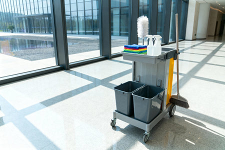 A cleaning cart is ready for use in a bright, modern office building with large windows and natural lightの写真素材