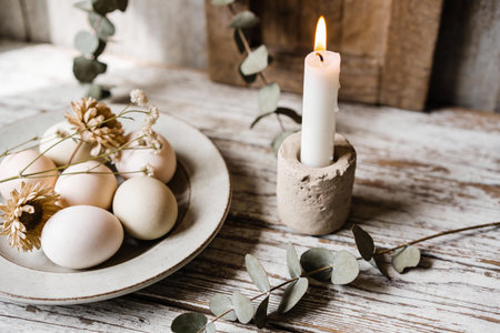 A serene still life composition featuring natural Easter eggs and a lit candle, evoking a sense of calm and traditionの写真素材