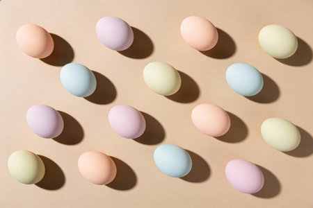 A collection of pastel-colored Easter eggs are artfully arranged in a symmetrical pattern, casting...
