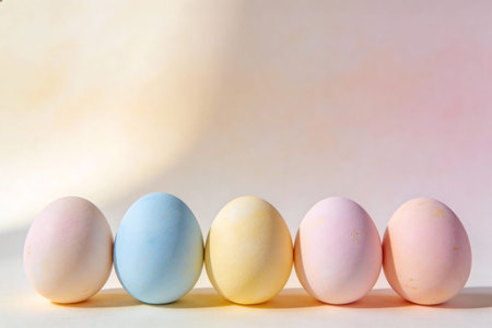A row of five delicately colored Easter eggs in soft pastel shades creates a charming and festive...