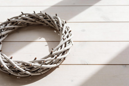 A simple, handcrafted wreath made of natural twigs, painted white, rests on a weathered wooden...