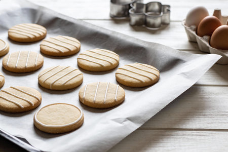 A batch of delicious round sugar cookies decorated with delicate white icing lines sits on a baking...