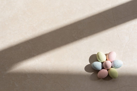A cluster of seven small, speckled pastel Easter eggs arranged like petals around a central egg,...