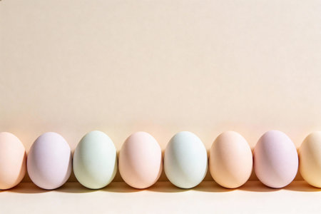A line of pastel colored Easter eggs casting gentle shadows on a plain, light-colored surface,...
