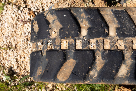 Detailed view of a heavy-duty tire with deep lugs, showing wear and embedded dirt and small stones