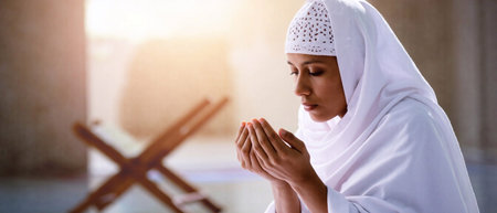 Arab woman wearing a white abaya making dua prayer near a mosque. Devotion to Allah in Islam