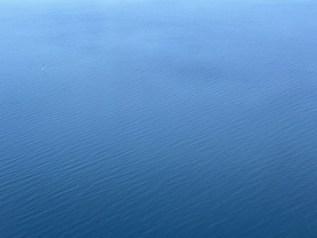 Calm blue water surface with gentle ripples. The scene captures a serene and tranquil atmosphere, ideal for relaxation and nature themes.の写真素材