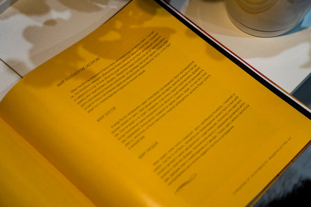 Odesa, Ukraine - July 30, 2024: Open book featuring yellow pages with text and graphics, creating a warm and inviting reading atmosphereの写真素材