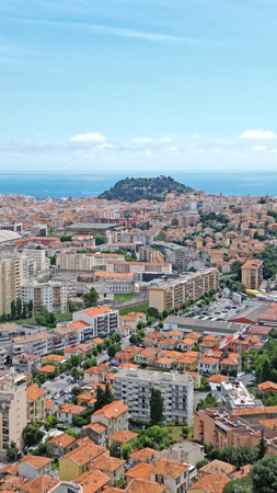 Stunning aerial perspective of a coastal city featuring terracotta rooftops, modern architecture, and greenery, highlighting the harmonious blend of nature and urban lifeの写真素材