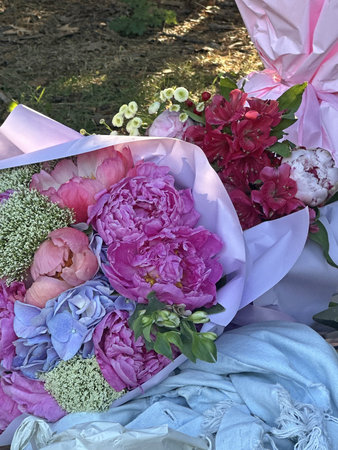 Assorted colorful flowers in a bouquet, featuring peonies and hydrangeas, elegantly wrapped in...
