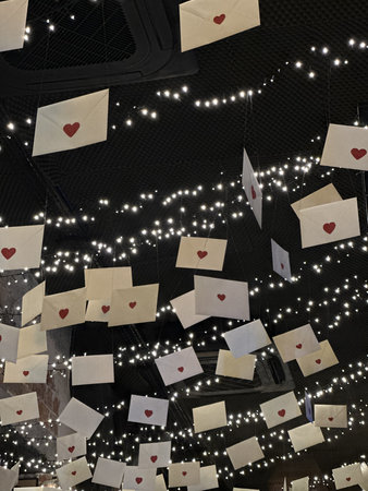 Envelopes with heart motifs hang from above, illuminated by soft fairy lights, creating a charming and romantic ambiance perfect for special occasionsの写真素材