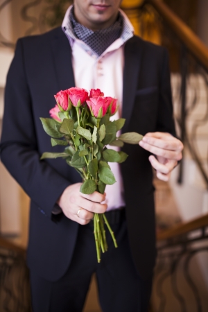 young man in a suit with roses in their handsの写真素材