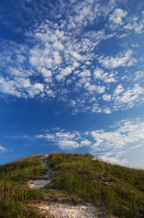 grassy hill to the road and the skyの写真素材