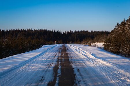 beautiful winter road through snowy fields,sunset and forestsの写真素材