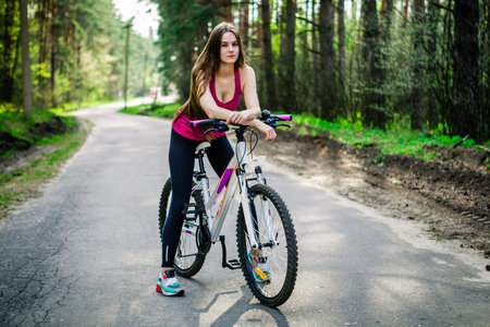 Sexy young beautiful sports girl on a white bicycle in the woodsの写真素材