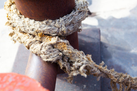 Close-up of a mooring rope with a knotted end tied around a cleatの写真素材