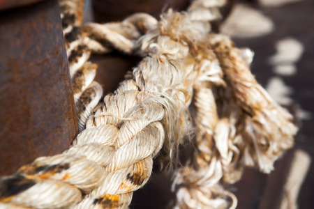 Close-up of a mooring rope with a knotted end tied around a cleatの写真素材