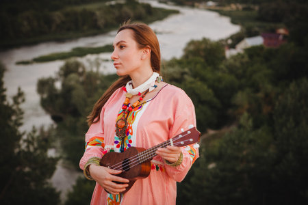 portrait young woman in ethnic dress lies with ukulele in handsの写真素材