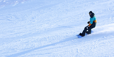a man in a multicolored jacket riding a snowboard.のeditorial素材