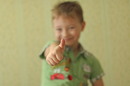 Boy showing thumbs up on a green background.の写真素材