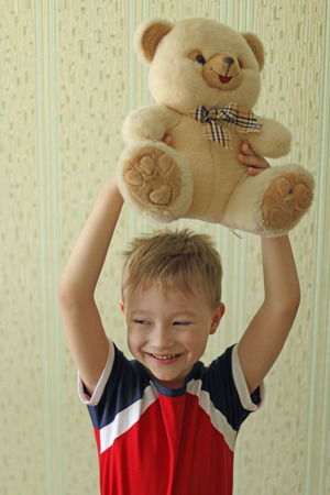 boy with Teddy bear. In the light of day on a green backgroundの写真素材