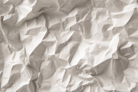 A detailed view of crumpled paper showing intricate patterns and textures. The folds and creases create a dynamic surface with varying shades of white and gray.の素材