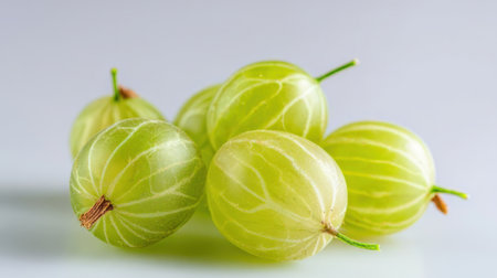 A group of vibrant green amla fruits sits on a light surface. These nutrient-rich berries showcase delicate stripes and a glossy appearance.の素材