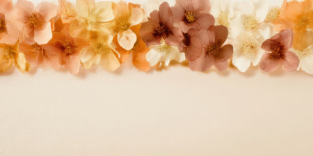 A variety of delicate flowers in soft shades of orange, peach, and cream are artistically arranged on a light surface, creating a serene and inviting atmosphere.の素材