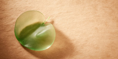 A single green leaf rests on a smooth brown surface, highlighting its delicate shape and vibrant color in a serene and minimalistic setting.の素材