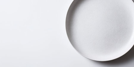 A minimalistic white plate is placed on a plain background. This scene highlights the smooth texture and clean design, inviting thoughts of serving delicious meals.の素材