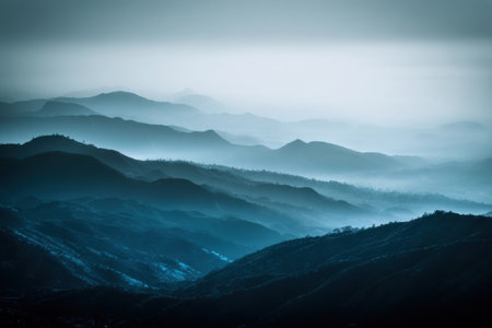 Layers of mountains stretch across the horizon, enveloped in mist and blues. The serene landscape creates a calming atmosphere, perfect for nature lovers and photographers alike.の素材
