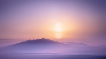 A serene sunrise casts soft colors over distant mountains, surrounded by gentle mist. The peaceful scene captures the beauty of early morning light and natures tranquility.の素材