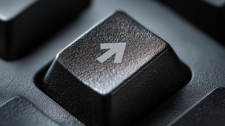 A close-up view of a black keyboard key featuring an upward arrow symbol. The key is focused and detailed, highlighting its texture and shape.の素材