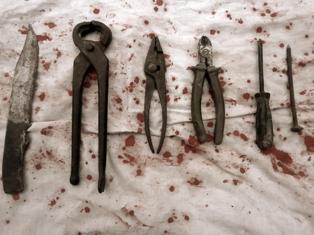 Old rusty tools on a white cloth stained with bloodの写真素材