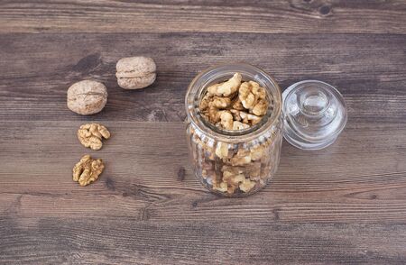 Glass jar with walnuts on a wooden backgroundの写真素材