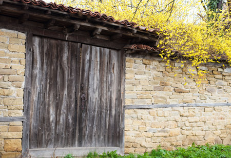 Detail of vintage wooden door, stone wall and yellow flowersの写真素材