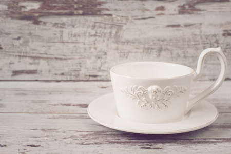 Simple rustic white crockery, empty dishes. A large cup of coffee in front angel. Wooden background, shabby chic, vintage tinting, copy spaceの写真素材