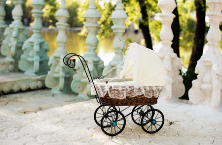 Doll's pram. Vintage doll stroller placed on the stairs to a beautiful lake. Retro cart dolls made...