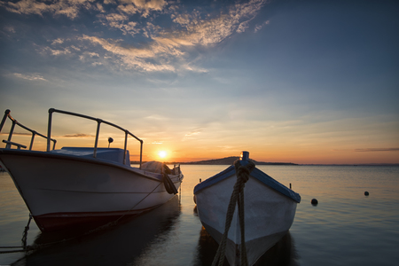 Two traditional wooden fishing boats in the sea. Fishing boats tied up in harbor at the end of the day. Sunset near the Black Sea coastの写真素材