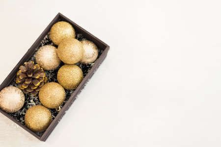 Golden Christmas balls in a wooden crate on a white rustic wooden background. Top viewの写真素材