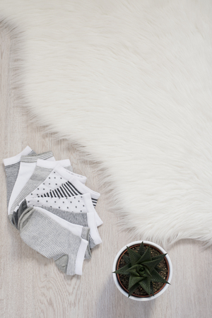 Different color socks on a gray wooden floor, fur carpet and plant. Shopping conceptの写真素材
