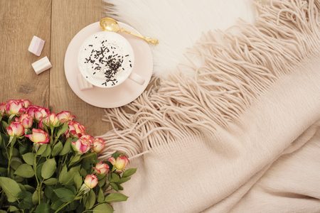 Cozy Winter Mornings. Cappuccino, bouquet of roses and a warm scarf on a white fur carpet on the floorの写真素材
