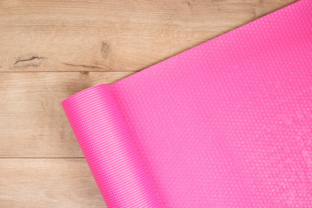 Pink yoga mat on a wooden background. Fitness concept, active lifestyle, body care concept. Wood...