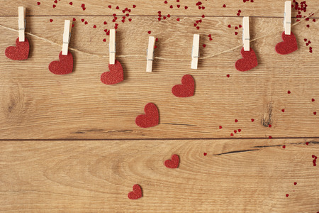 Valentine's Day concept. Heart shape garland. Red glitter hearts hanging on rope on wooden backgroundの写真素材