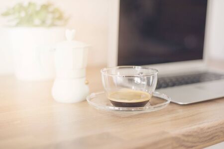 Morning Coffee. Working From Home.  Cup Of Coffee And Italian Coffee Maker In Blue. Bright And Clean Modern Minimalist Kitchen, Close Up. Laptop, Green Succulent Pot On Wooden Worktop. Glare, sun hazeの写真素材