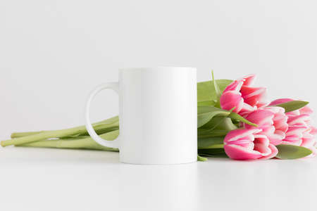 Mug mockup with bouquet of pink tulips on a white table.の写真素材