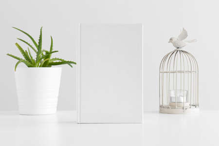 White book mockup with a succulent plant and a candle holder on a white table.の写真素材